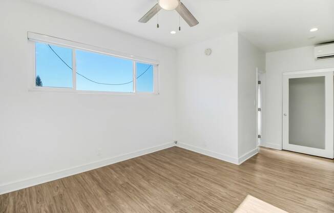 an empty living room with white walls and a wooden floor