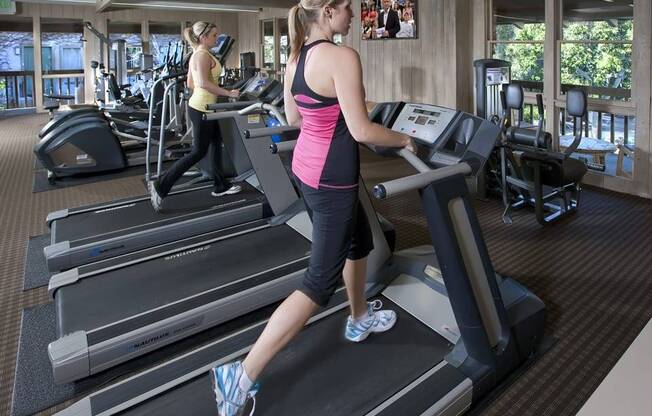 a woman running on a treadmill in a gym