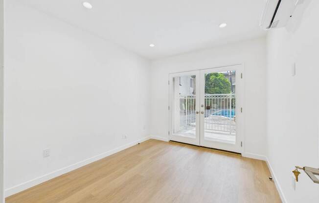 A room with a wooden floor and a sliding glass door leading to a balcony.