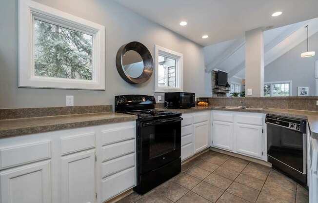 A kitchen with black appliances and white cabinets.at Camden Place, Dublin, OH