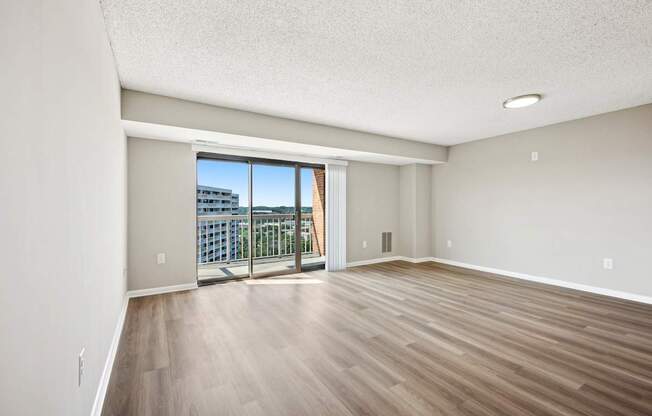 A room with wooden flooring and a sliding glass door leading to a balcony.