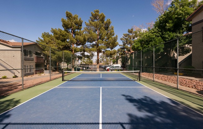 a tennis court with a fence around it and trees
