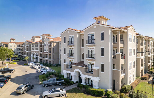A large apartment complex with multiple buildings and cars parked in the lot.