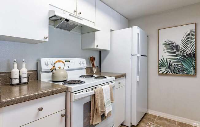 A kitchen with white appliances and a painting on the wall.