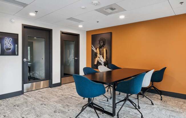 A conference room with a table and chairs and a painting on the wall.