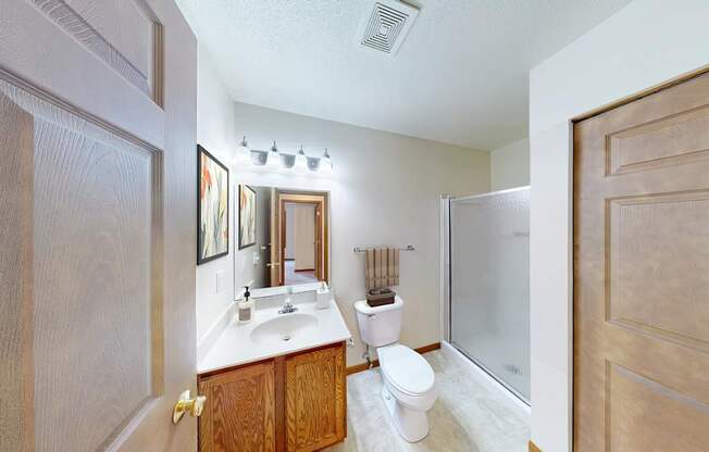 A bathroom with a toilet, sink, and mirror.