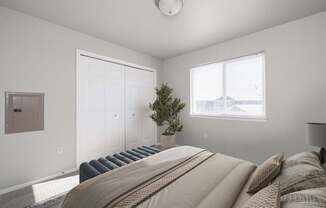 A bedroom with a large bed and a small tree in a pot.