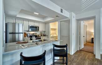 a kitchen with a bar and two chairs in front of a
