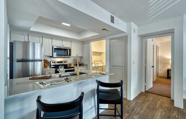 a kitchen with a bar and two chairs in front of a