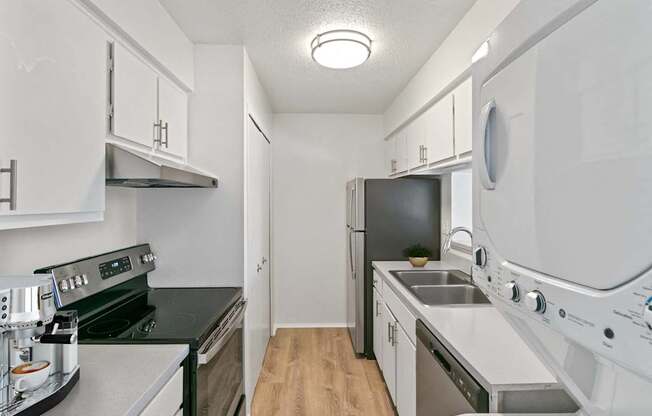 A small, white kitchen with a black stove top oven and a black dishwasher.