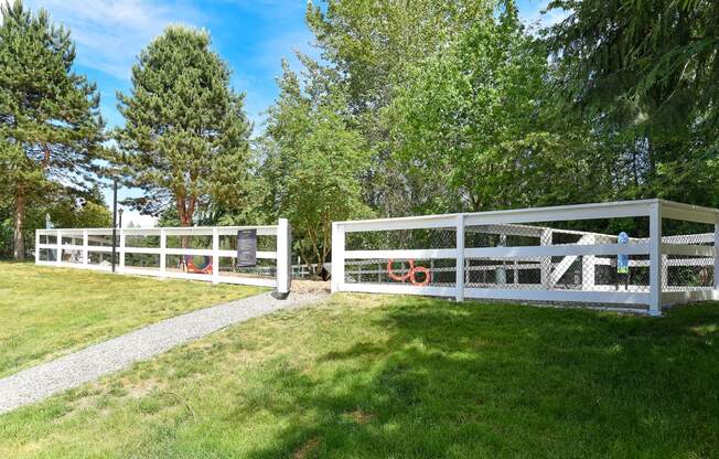 a white fence in a grassy area with trees in the background