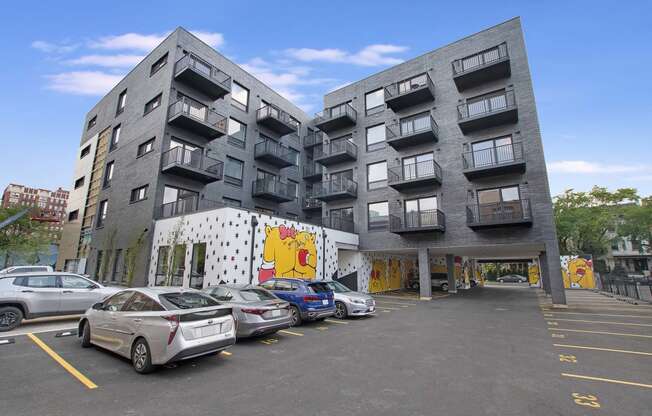 a grey apartment building with cars parked in front of it