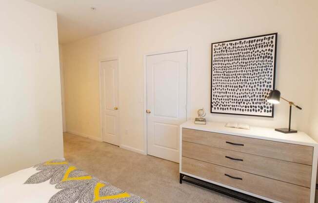 A bedroom with a bed, dresser, and a wall hanging picture.