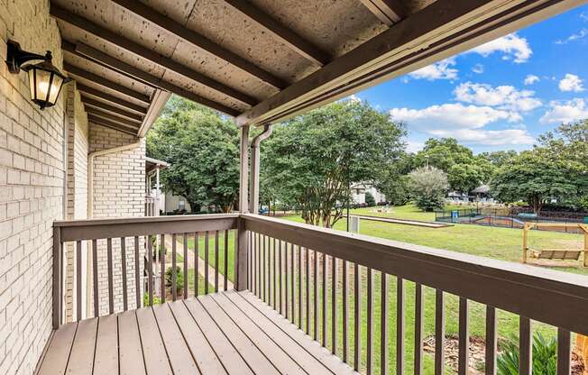 A wooden deck with a railing and a lamp on the wall.
