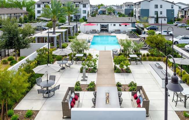 A pool surrounded by a patio with chairs and a table.