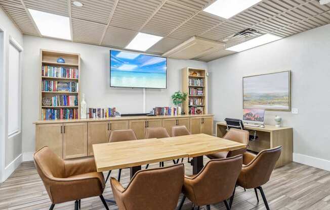 A conference room with a large table, chairs, and a screen displaying a beach scene.