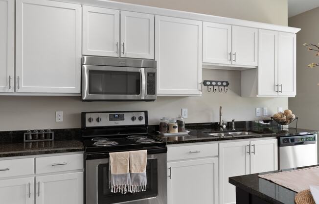 a white kitchen with stainless steel appliances and white cabinets at Hayden Lofts, Dublin, Ohio