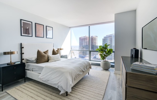 a bedroom with a large window and a bed and a rug