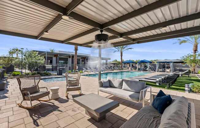 A patio with a rocking chair and a table with a cushion on it.