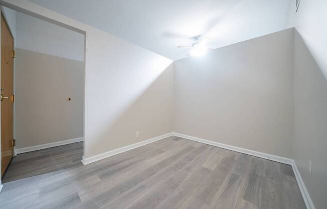 A room with a ceiling fan and wood flooring.