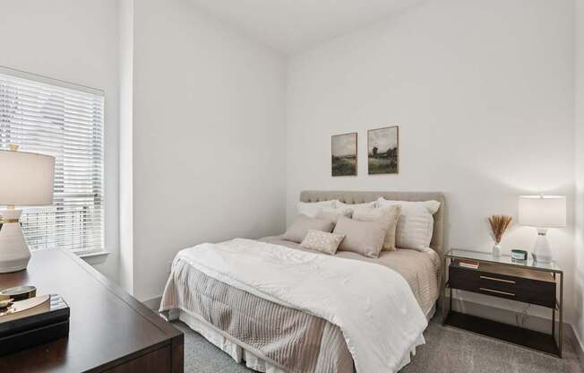 A bedroom with a large bed and a nightstand with a lamp.