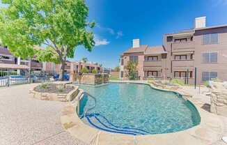 A swimming pool surrounded by a stone patio and a tree.