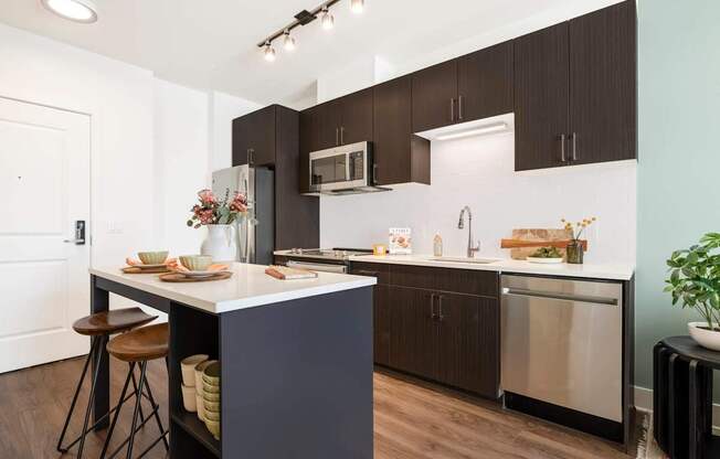 A kitchen with a white counter top and brown cabinets.at The Vale at the Parks, Washington, DC