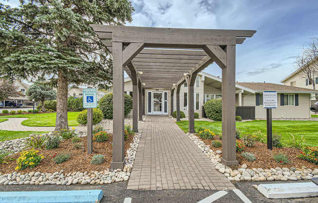 Aurora, CO Apartments – Aurora Meadows – A covered walkway leads to our leasing office with a sign in front of it.