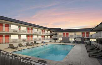 A swimming pool is surrounded by sun loungers in a courtyard.