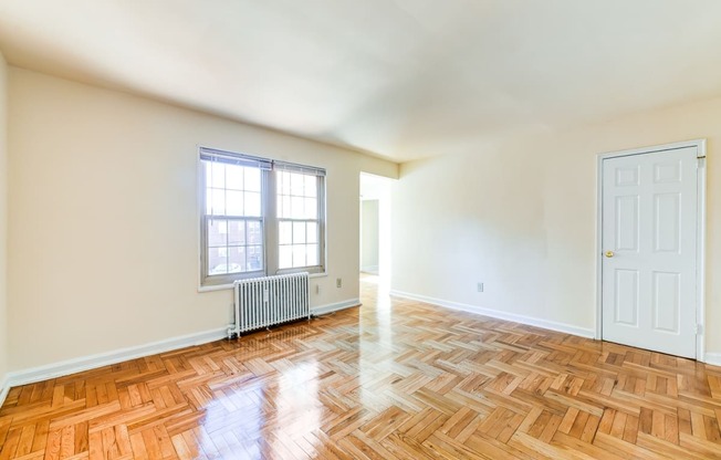 vacant living area with hardwood flooring and large windows at richman apartments in washington dc