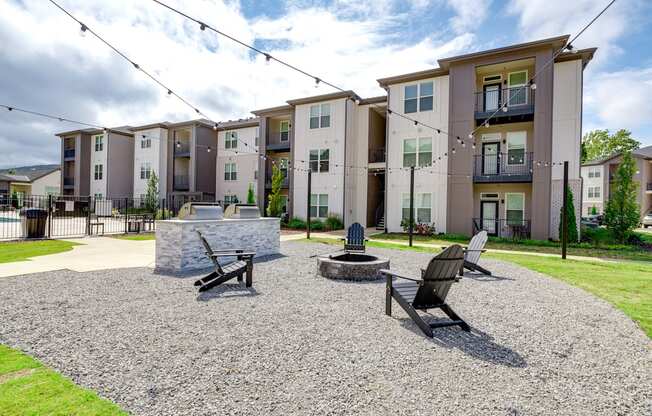 an outdoor area with a fire pit and chairs in front of an apartment building