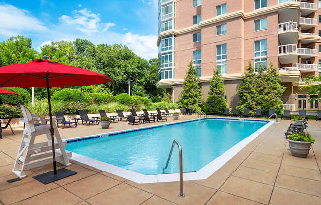 A red umbrella stands over a pool in a courtyard.