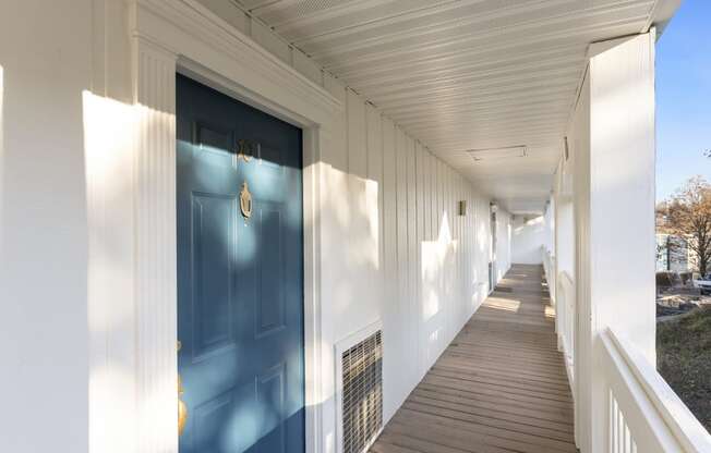 a long porch with a blue door on a white building