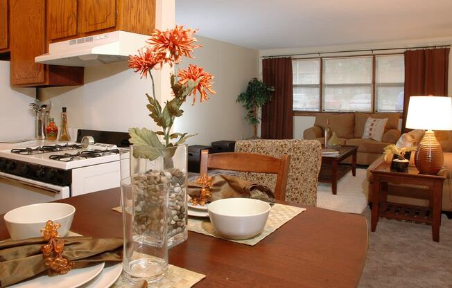 a living room with a wooden table and a kitchen in the background