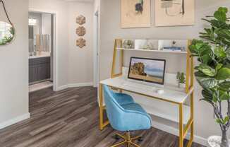 a computer desk with a blue chair and a potted plant in a room with a bathroom