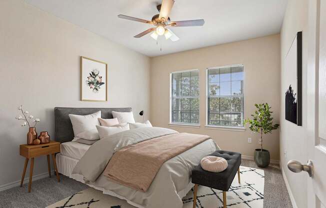 A bedroom with a bed, a chair, and a ceiling fan.