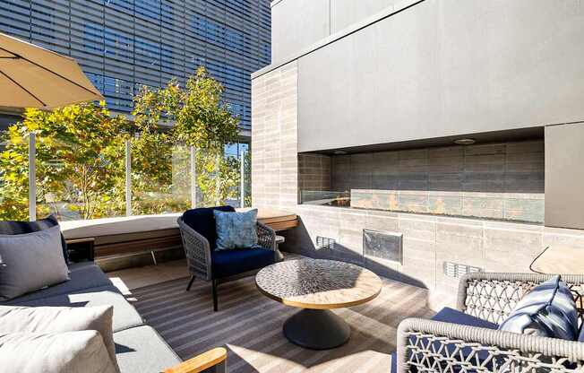 A patio with a couch, chairs, and a table with a blue cushion.