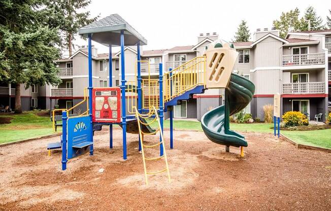 A playground with a green slide and a blue and yellow play structure. at Notch 8, Tacoma, Washington
