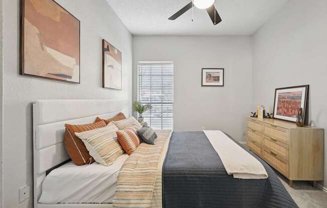 A bedroom with a bed, dresser, and artwork on the walls.