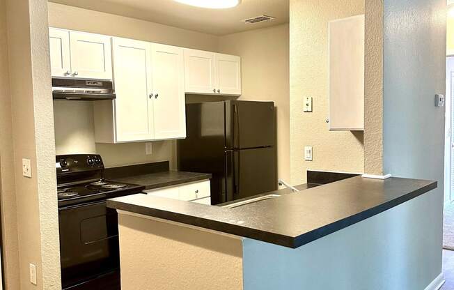 a kitchen with a countertop and a black refrigerator at Aqua Bay Apartments in Naples, FL 34116