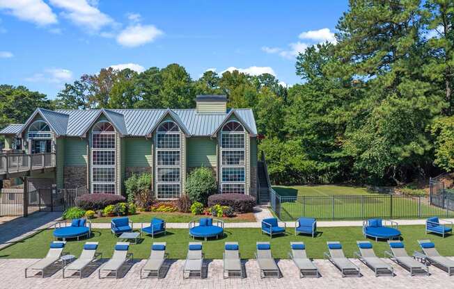 a patio with lounge chairs and a house with a yard and trees