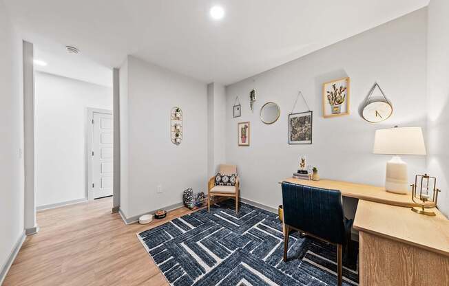 A room with a blue chair and a desk with a lamp on it