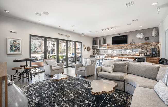 A modern living room with a black and white rug, a grey sofa, and a flat screen TV mounted on the wall.
