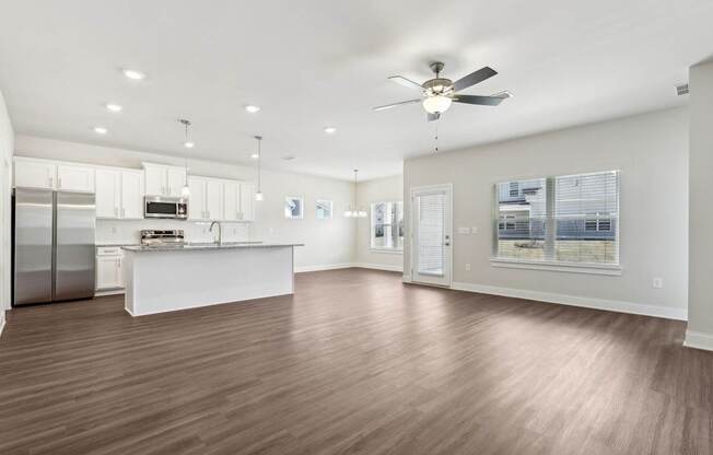 A spacious kitchen with a refrigerator, sink, and a ceiling fan.