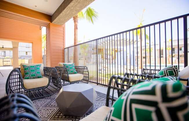 a living room with chairs and a table and a balcony with palm trees