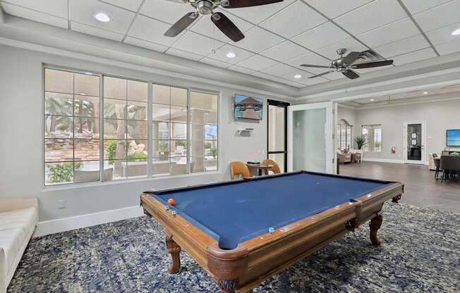 A pool table in a room with a ceiling fan.