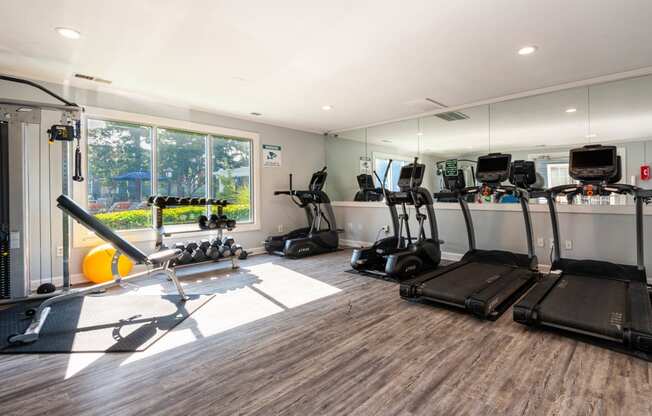 a gym with cardio equipment and a large window