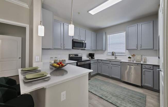 A kitchen with a white island and grey cabinets.