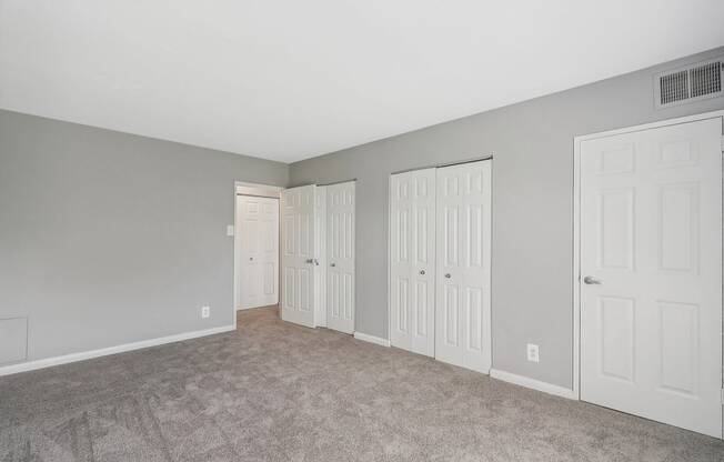 a bedroom with three closets and a carpeted floor