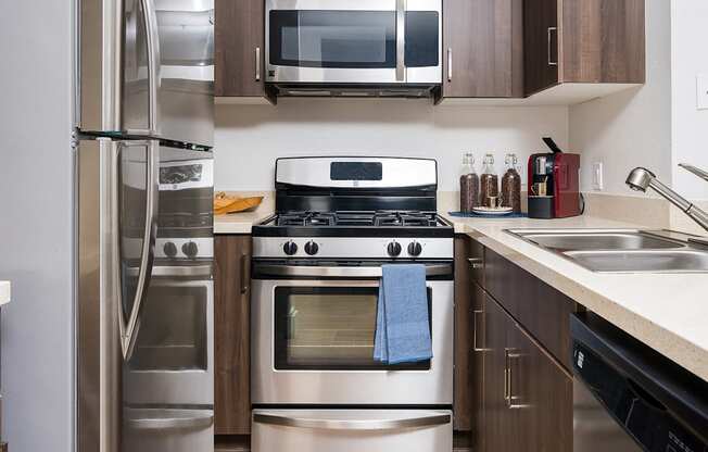 Miracle Mile Los Angeles Apartments - The Preston - Kitchen with Plank Wood Style Flooring, Stainless-Steel Appliances, Quartz Countertops, and Wooden Cabinets